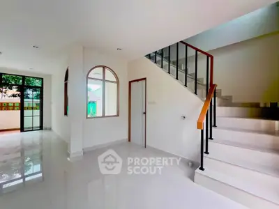 Spacious modern interior with staircase and large windows in a bright living area.