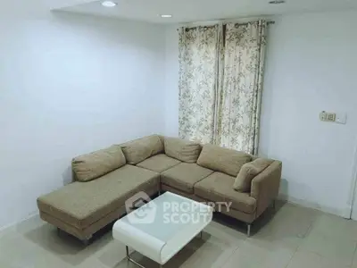 Cozy living room with beige sectional sofa and modern white coffee table.