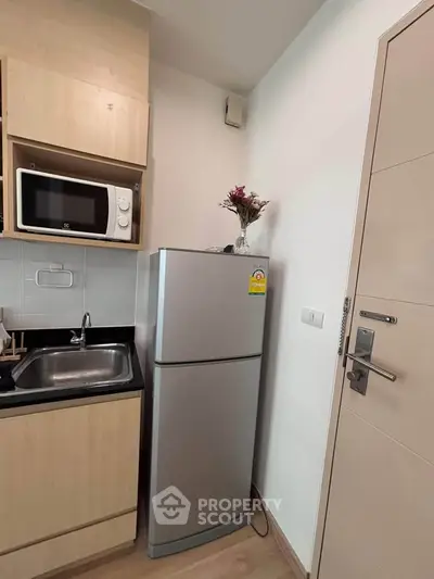 Compact kitchen with modern appliances including fridge and microwave, ideal for urban living.