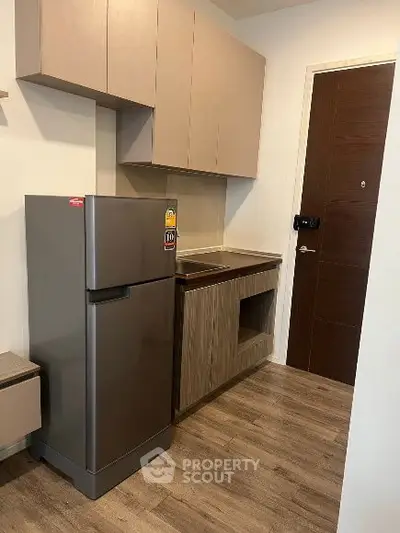 Modern compact kitchen with sleek cabinets and stainless steel fridge