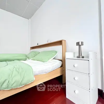 Cozy bedroom with modern decor and green accents, featuring a stylish bed and sleek bedside table.