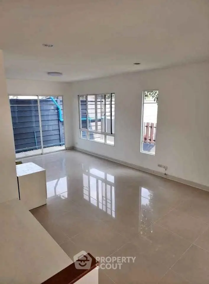 Spacious and bright living room with large windows and tiled flooring