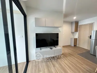Modern living room with sleek TV setup and wooden flooring in a stylish apartment.