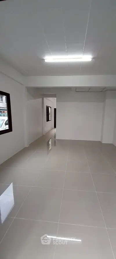 Spacious empty room with glossy tiled flooring and bright lighting