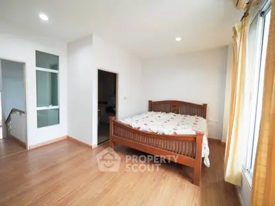 Spacious bedroom with wooden flooring and natural light