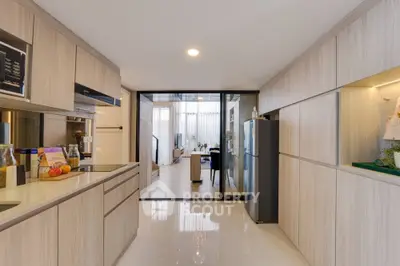 Modern kitchen with sleek cabinetry and open layout leading to dining area