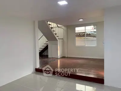 Spacious modern living area with elevated wooden flooring and staircase, perfect for stylish urban living.