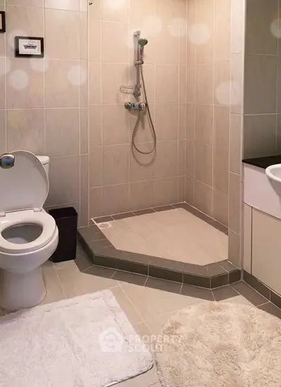 Modern bathroom with shower and toilet in a stylish tiled setting.