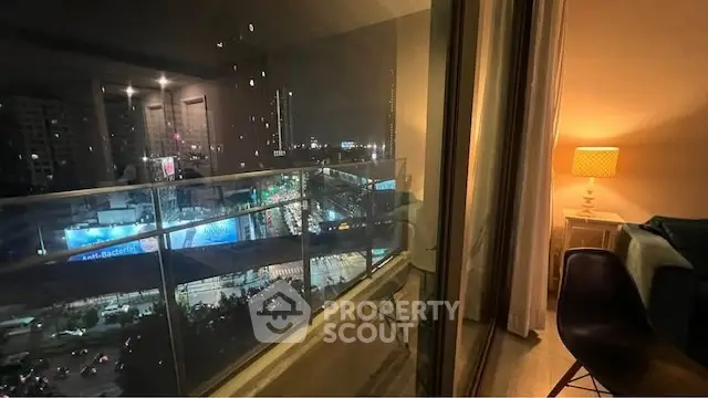 Stunning city view from modern apartment balcony at night with cozy interior lighting.