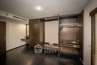 Spacious bedroom with built-in wooden wardrobe and dark flooring
