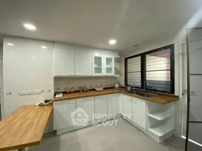 Modern kitchen with sleek white cabinets and wooden countertops, featuring a spacious layout and ample natural light.