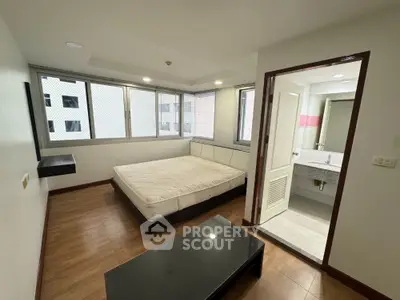 Modern bedroom with ensuite bathroom and large windows in urban apartment