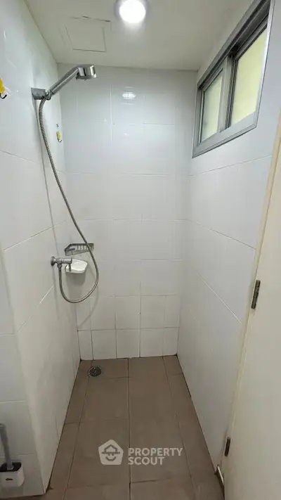 Compact bathroom with shower and tiled walls, ideal for efficient space use.
