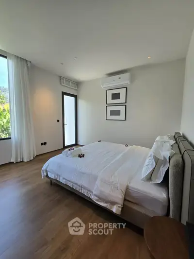 Modern bedroom with elegant decor and natural light, featuring a comfortable bed and stylish wooden flooring.