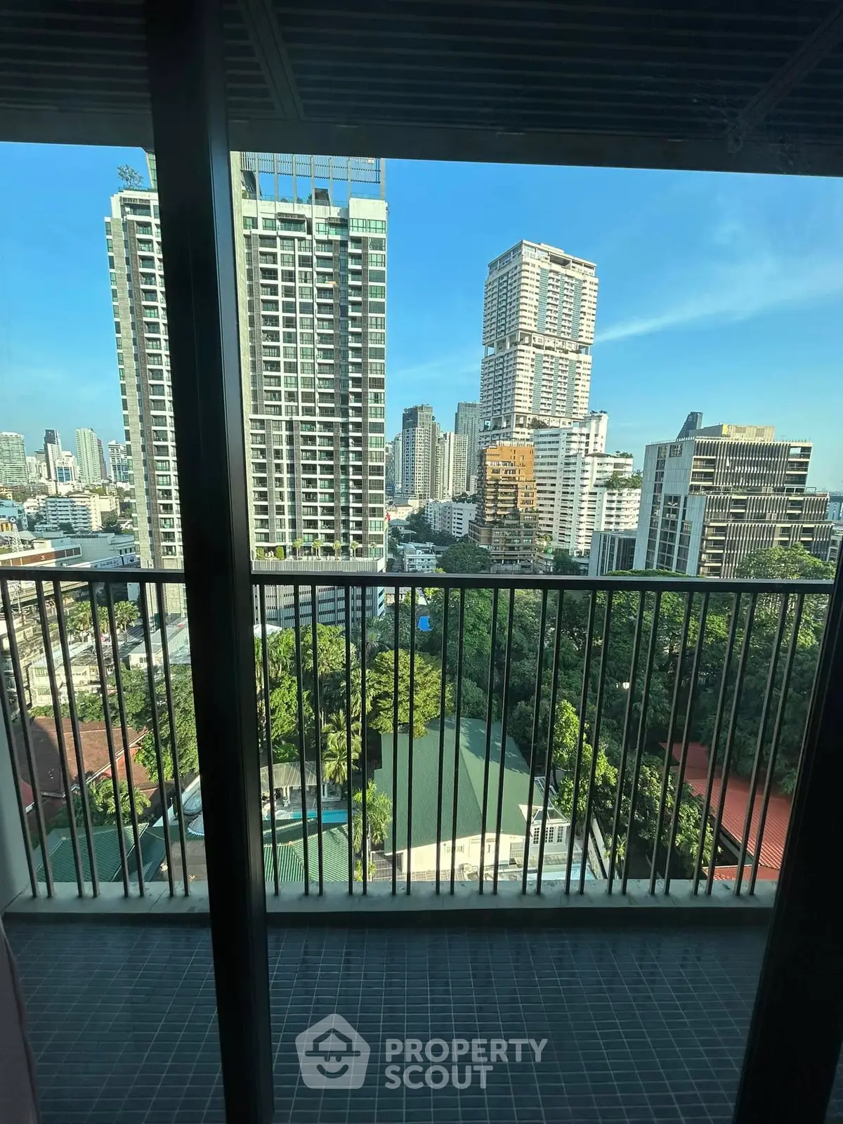 Stunning cityscape view from a high-rise balcony overlooking lush greenery and modern skyscrapers.
