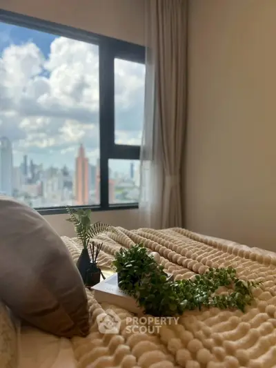 Cozy bedroom with stunning city view through large window, featuring plush bedding and elegant decor.
