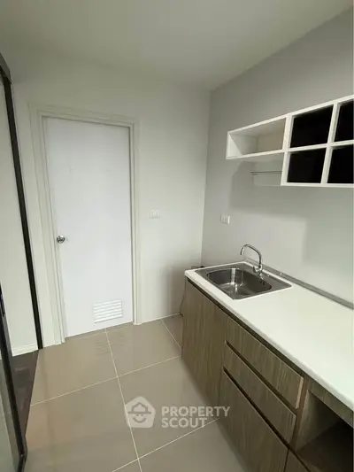 Modern kitchen with sleek cabinetry and stainless steel sink in a minimalist design.