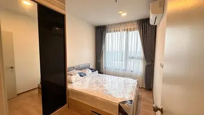 Cozy bedroom with large window and modern furnishings in a stylish apartment.