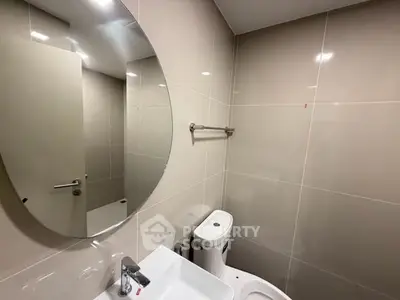 Modern bathroom with sleek fixtures and large mirror in contemporary apartment.