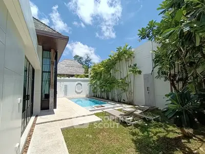 Luxurious private villa with pool and lush garden under clear blue sky.