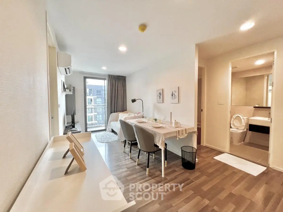 Modern open-plan living room with dining area and balcony access in a stylish apartment.