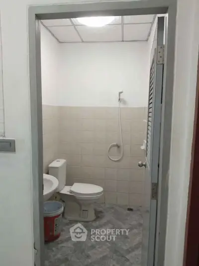 Compact bathroom with shower and toilet in a tiled setting, ideal for efficient space use.