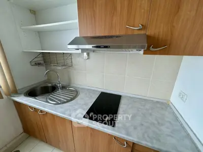 Compact kitchen with electric cooktop and stainless steel sink in modern apartment