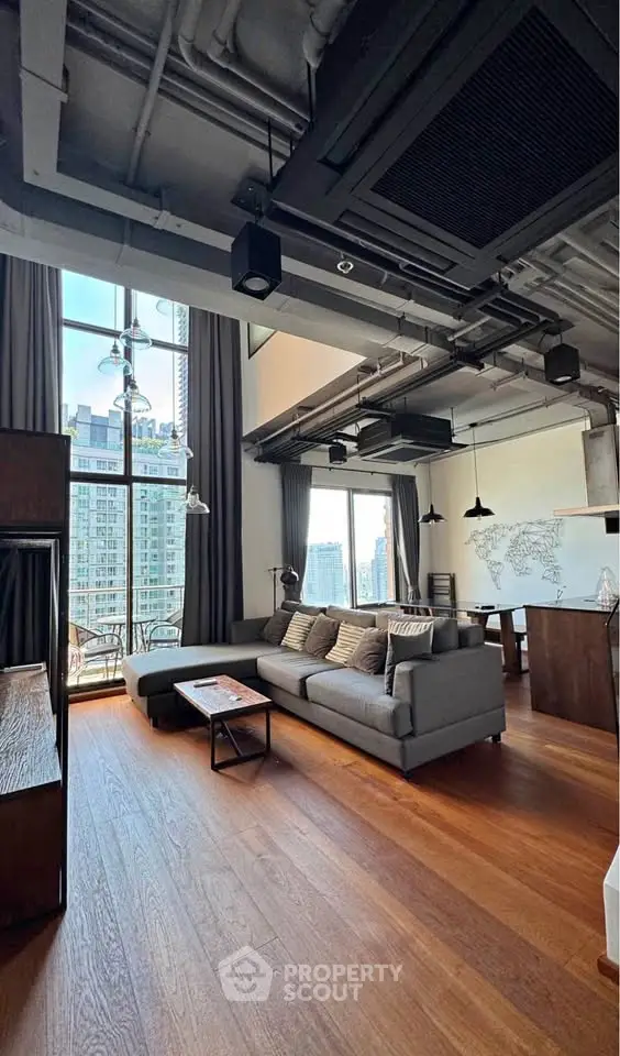 Spacious modern living room with high ceilings and city view, featuring stylish decor and open layout.