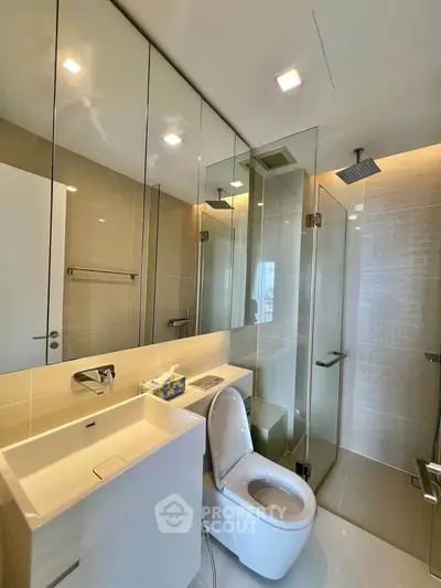 Modern bathroom with glass shower and sleek fixtures in luxury apartment.