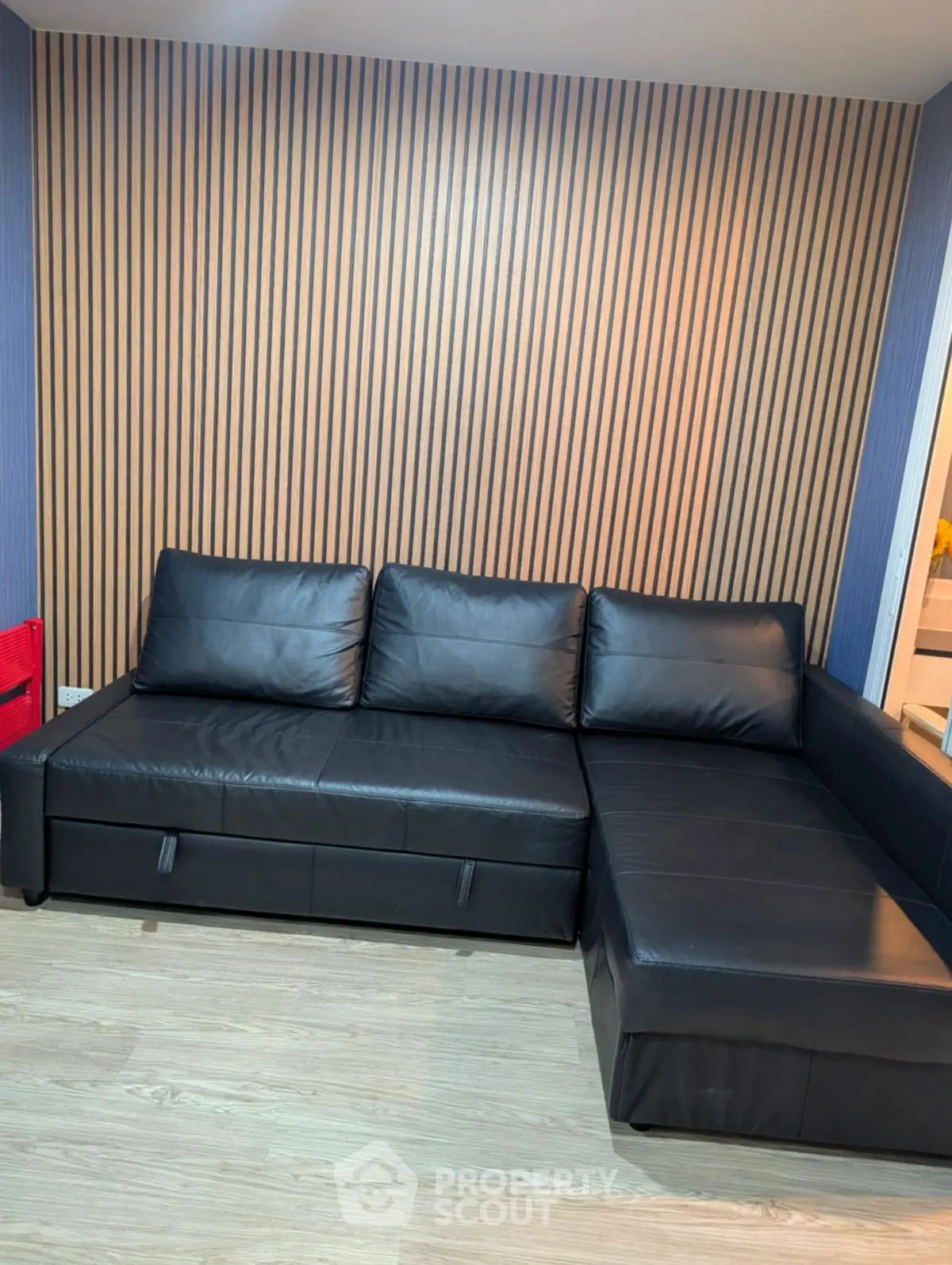 Modern living room with sleek black leather sectional sofa and stylish wood panel accent wall.