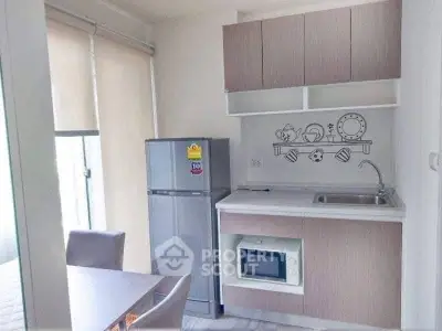 Modern compact kitchen with sleek cabinetry and appliances in a bright apartment.