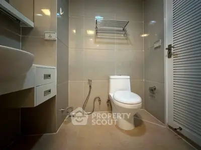 Modern bathroom with sleek fixtures and neutral tiles, featuring a wall-mounted sink and a spacious layout.