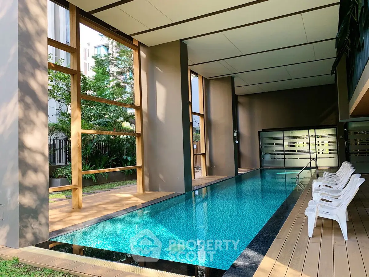 Luxurious indoor pool with modern design and seating area in upscale property.