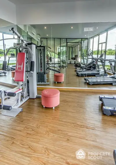 Spacious gym with modern equipment and mirrored walls in luxury apartment complex