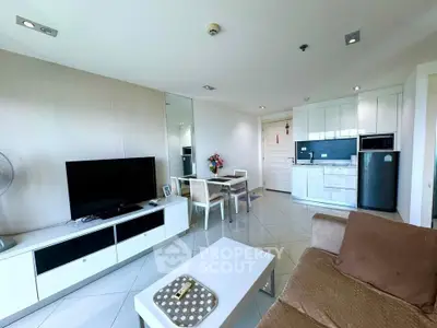 Modern living room with open kitchen, sleek furniture, and bright natural lighting.