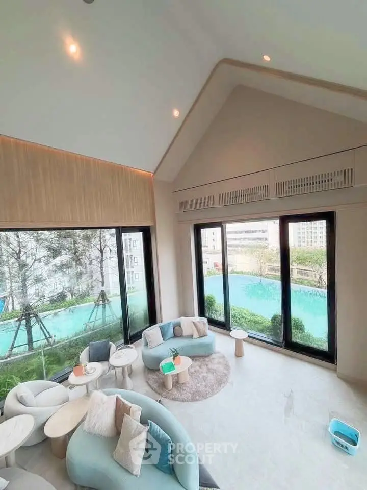 Luxurious living room with large windows offering stunning pool view, elegant furniture, and high ceilings.