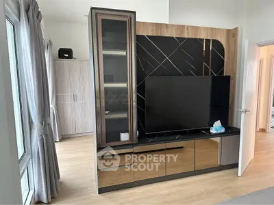 Modern living room with sleek TV unit and large windows for natural light