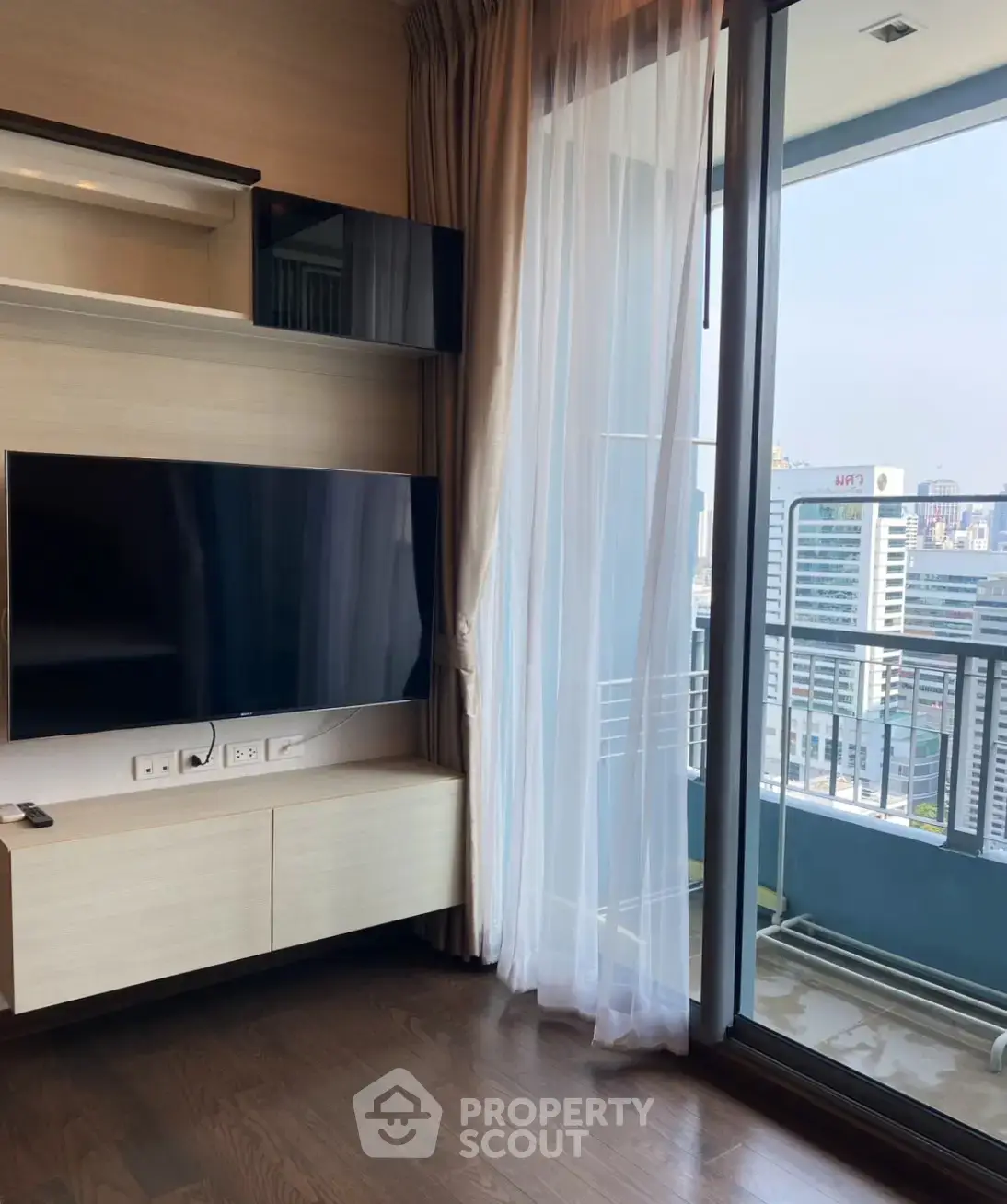 Modern living room with large TV and balcony view in urban apartment