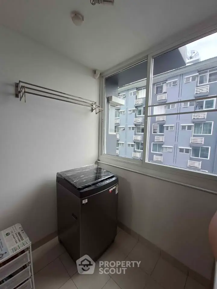 Compact laundry area with washing machine and city view in modern apartment.