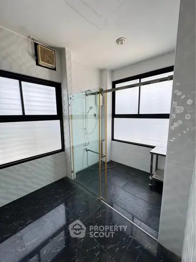 Spacious modern bathroom with glass shower and large windows