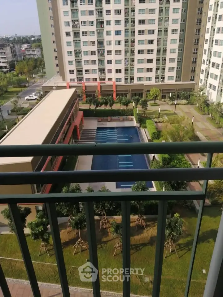 Modern apartment complex with pool view from balcony, lush greenery and urban setting.