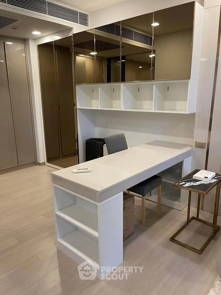 Modern study area with sleek desk and mirrored cabinets in a stylish apartment.