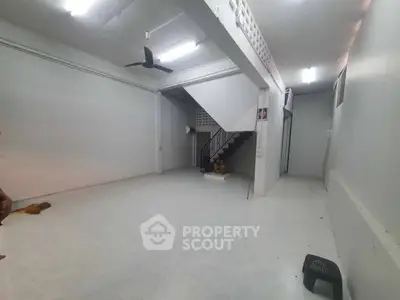 Spacious interior with staircase and ceiling fan, ideal for versatile use.