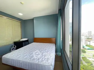 Spacious bedroom with large window offering stunning city views, featuring a comfortable bed and modern decor.