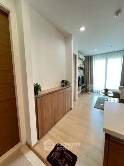 Modern living room with wooden flooring, stylish decor, and natural light from large windows.