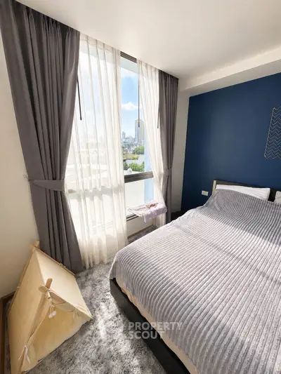 Bright and cozy bedroom with city view, featuring elegant curtains and a plush bedspread.