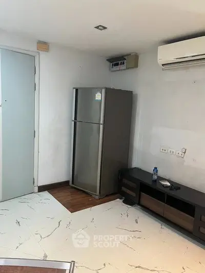 Modern apartment interior with sleek fridge and air conditioning unit, featuring stylish flooring and minimalist decor.