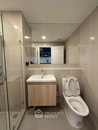 Modern bathroom with sleek fixtures and glass shower in contemporary apartment.