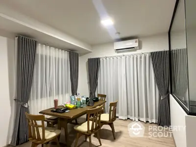 Modern dining area with wooden table and chairs, featuring elegant curtains and air conditioning.