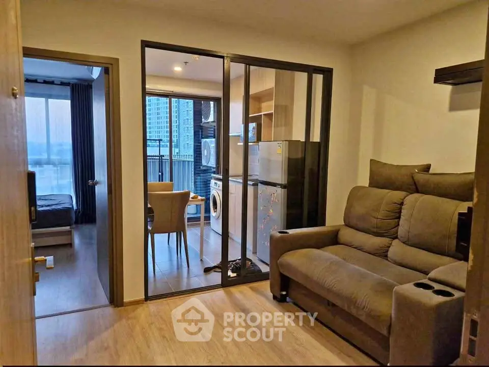 Modern apartment interior with cozy living room and open kitchen layout featuring a washing machine.